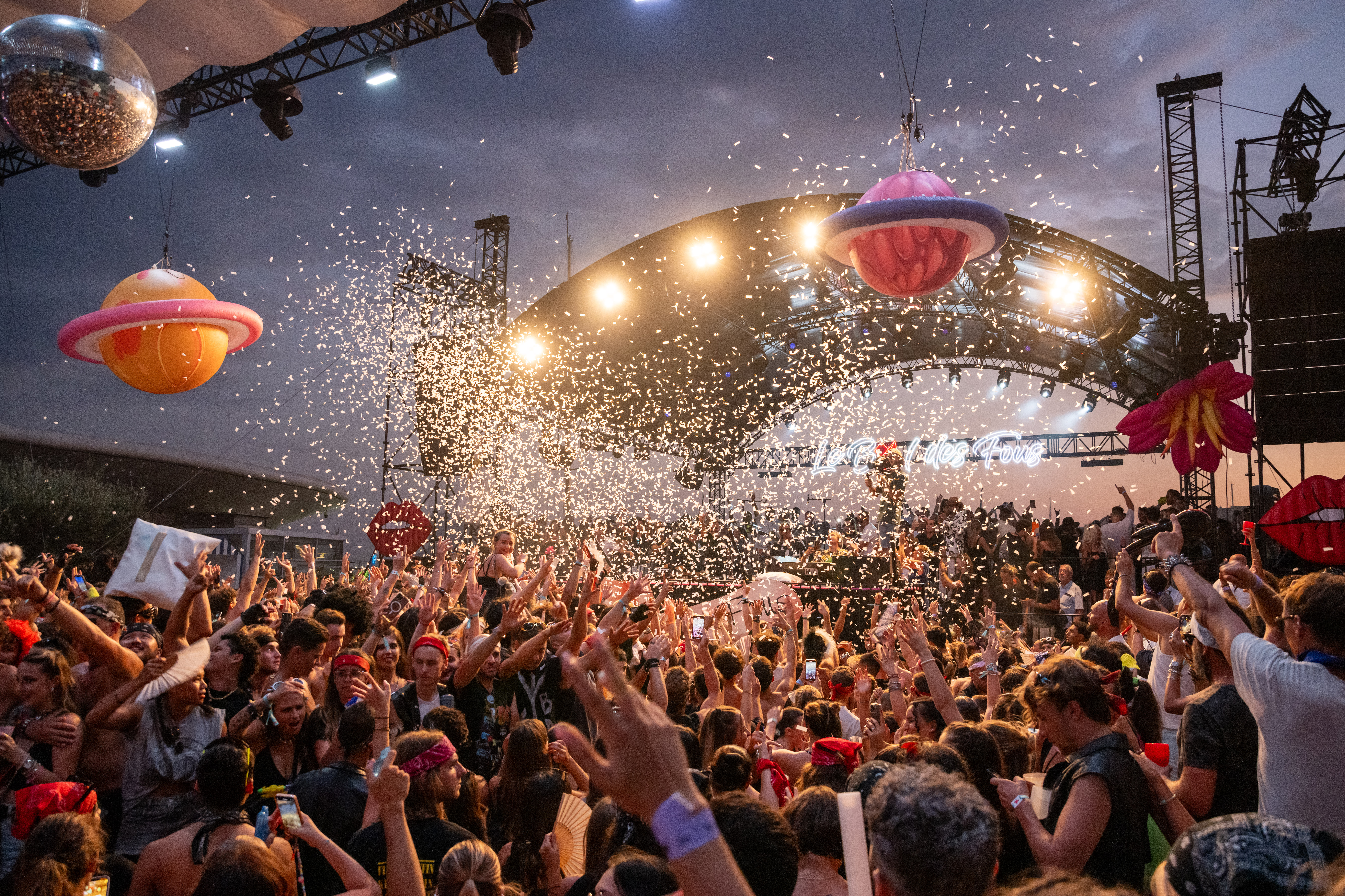 Festival en plein air avec une foule devant une scène décorée